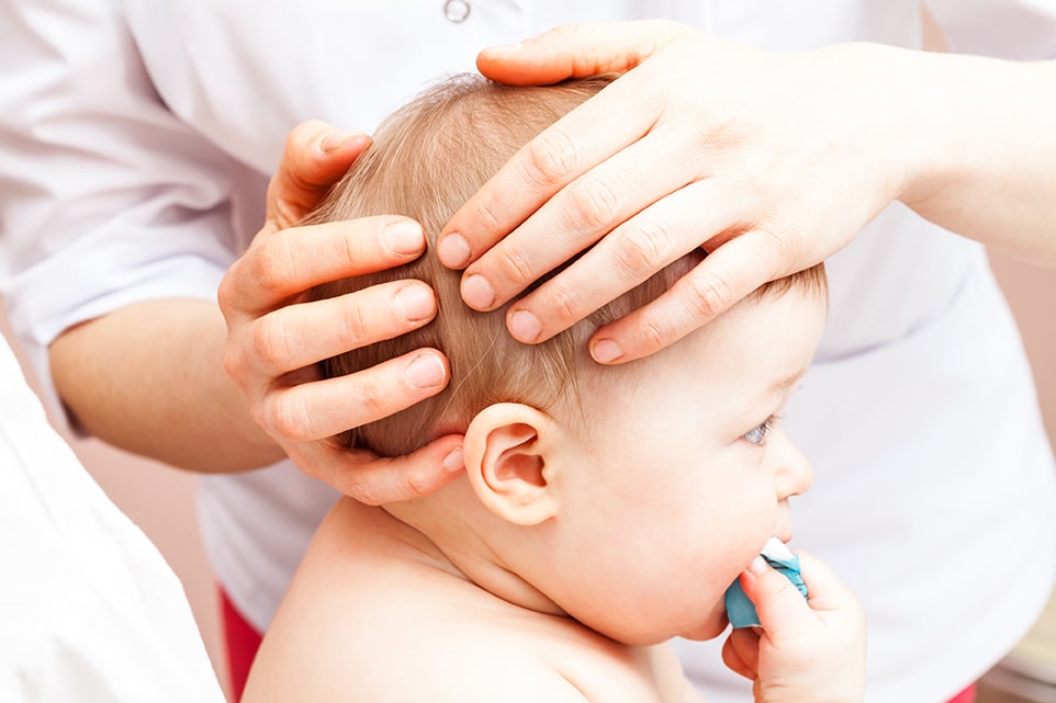 Osteopath practicing cranial osteopathy on baby